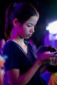 Side view of young woman holding smart phone