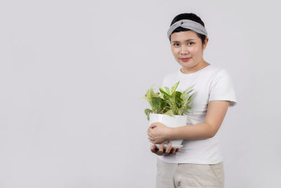 Portrait of beautiful young woman standing against white background