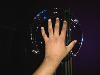 Close-up of hand holding glass against black background