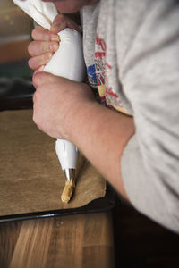 Midsection of man preparing food with icing bag at table