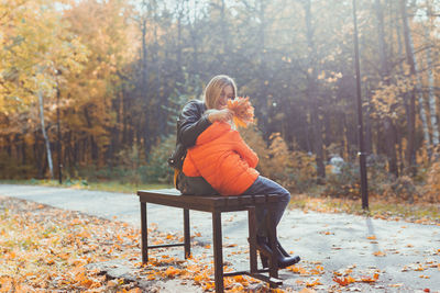 Woman sitting on sidewalk in forest during autumn