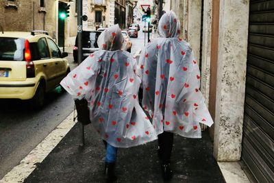Rear view of people in raincoat walking on street
