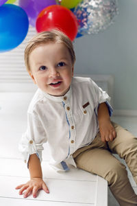 Portrait of a child boy two years old sitting on a wooden floor with balls and number two