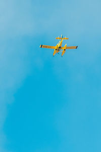 Low angle view of airplane flying against clear blue sky