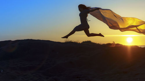 Low angle view of man jumping at sunset