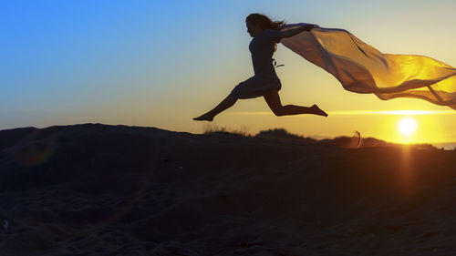 View of woman jumping at sunset