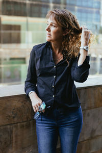Portrait of young woman standing against building