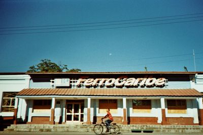 Man riding bicycle on building against sky