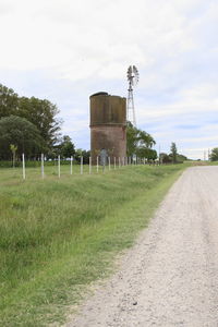 Built structure on field by road against sky
