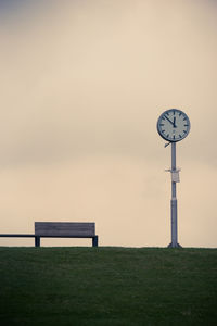 Empty bench on field against sky during sunset