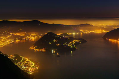 Aerial view of illuminated city by lake iseo against sky at night