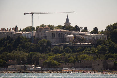 Buildings by river against sky in city