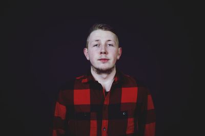 Portrait of young man against black background