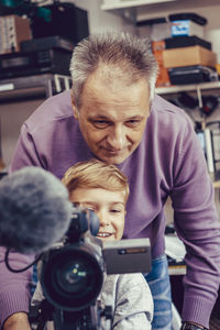 Happy boy learning to film with video camera.