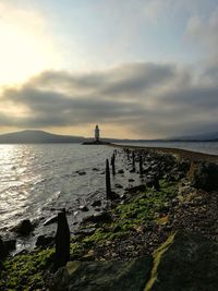 Narrow scythe in the sea leading to the lighthouse against cloudy morning sky