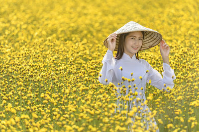 Portrait of girl with yellow flowers on field