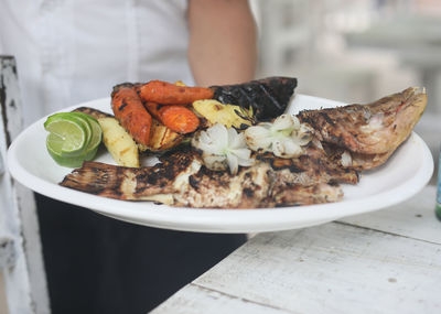 Close-up of hand holding food in plate