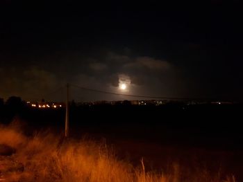 Illuminated field against sky at night