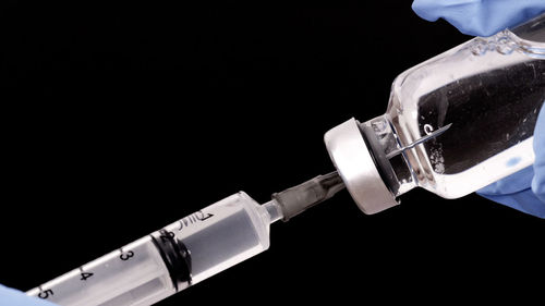 Close-up of hand holding guitar against black background