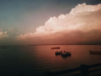 Boats in sea at sunset