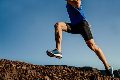 Low angle view of man running against blue sky