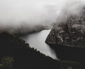 Scenic view of river by mountains against sky