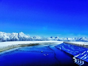 Scenic view of river against blue sky during winter
