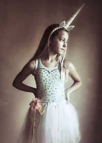 Thoughtful girl wearing costume with hands on hip against wall