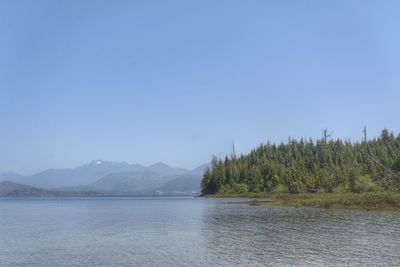 Scenic view of lake and mountains against clear blue sky