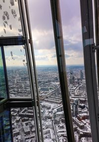 Buildings in city against sky seen through window