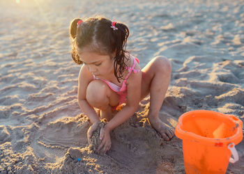 Young girl is playing with beach toys in the sand