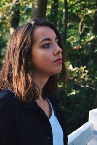 Close-up of young woman standing against trees