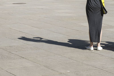 Low section of woman standing on footpath