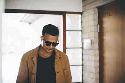 Portrait of young man wearing sunglasses standing indoors