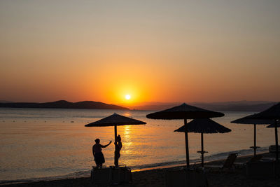 Silhouette man on beach against sky during sunset