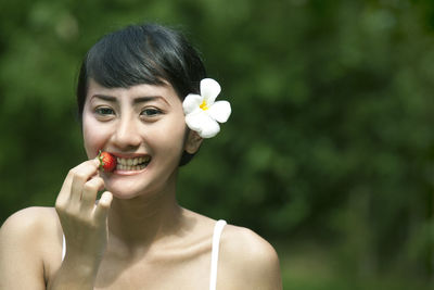 Close-up portrait of a smiling young woman eating strawberry