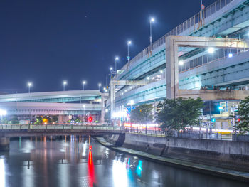 Illuminated bridge over river at night
