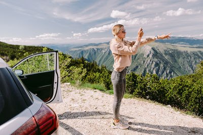 Woman standing by car on mountain road