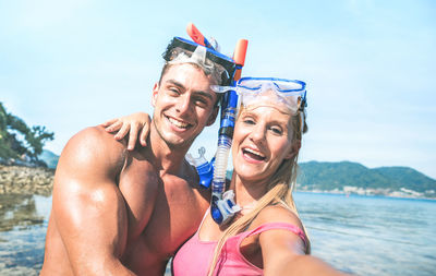 Portrait of smiling man and woman in sea against sky