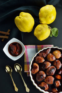 Concept with baked quinces in bakeware,raw quinces,cinnamon sticks and gold spoon 