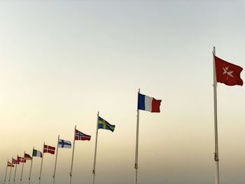 Low angle view of person holding flag against clear sky