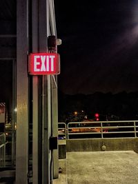 Illuminated road sign against sky at night