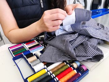 Midsection of woman sewing textile at home