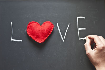 Cropped hand of woman writing love text on blackboard