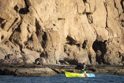 One woman paddling on a seat on top kayak close to the shore of carmen island in loreto, baja california, mexico.