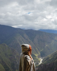 Rear view of man looking at mountains against sky