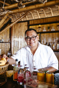 Portrait of smiling bartender with eyeglasses at counter in resort