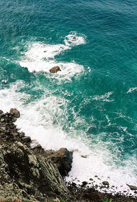 High angle view of sea waves splashing on rocks