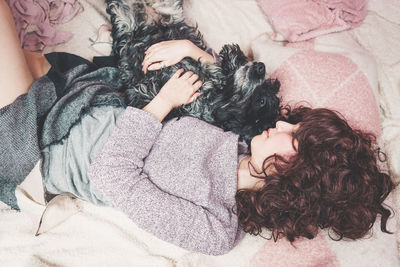 Woman with dog lying on bed at home