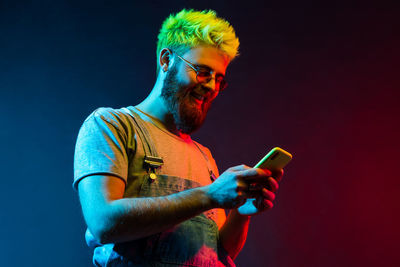 Smiling man using mobile phone against colored background